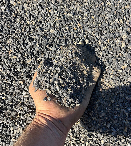 Hand holding a small pile of crusher dust