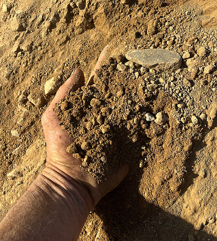 Hand scooping up roadbase and padmix at quarry